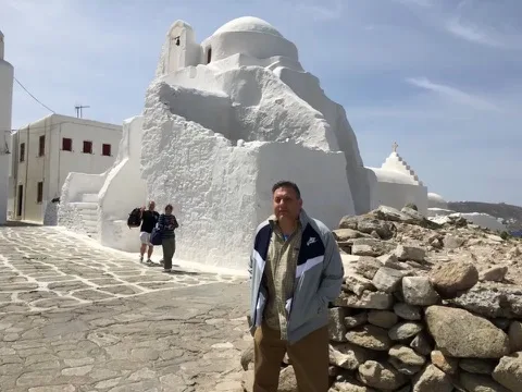 Scott beside a whitewashed chapel — Mykonos