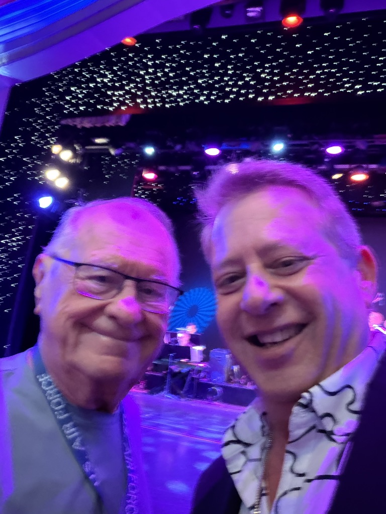 Purple lights and a shared milestone: Scott A. Astin taking a selfie with a fellow traveler under purple theater lights