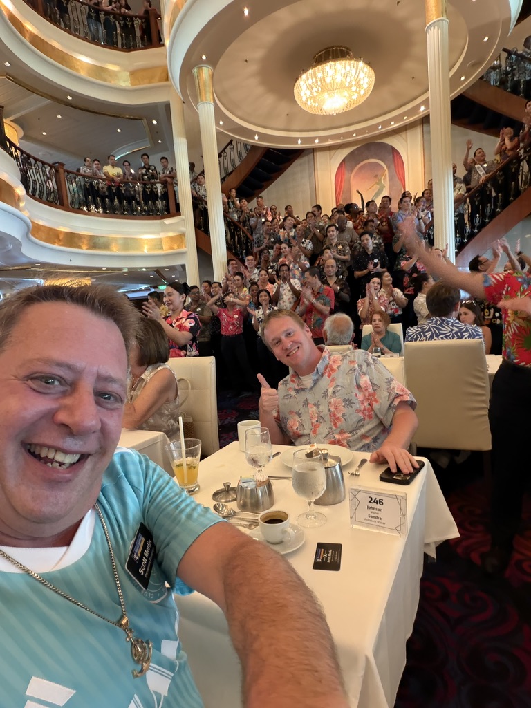 A dining room full of celebration: Scott A. Astin smiling from a table in a crowded dining room