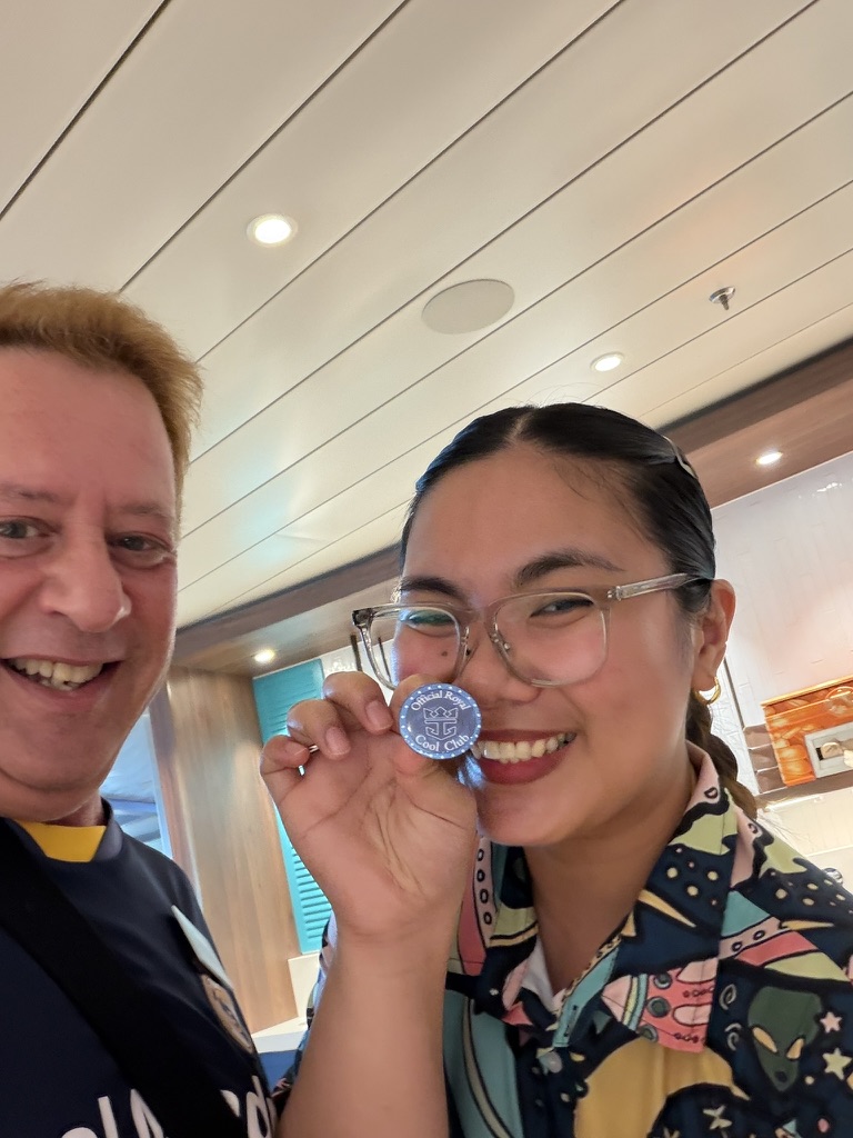 A smile behind the work: Scott A. Astin beside a crew member in a patterned uniform holding a blue keepsake pin