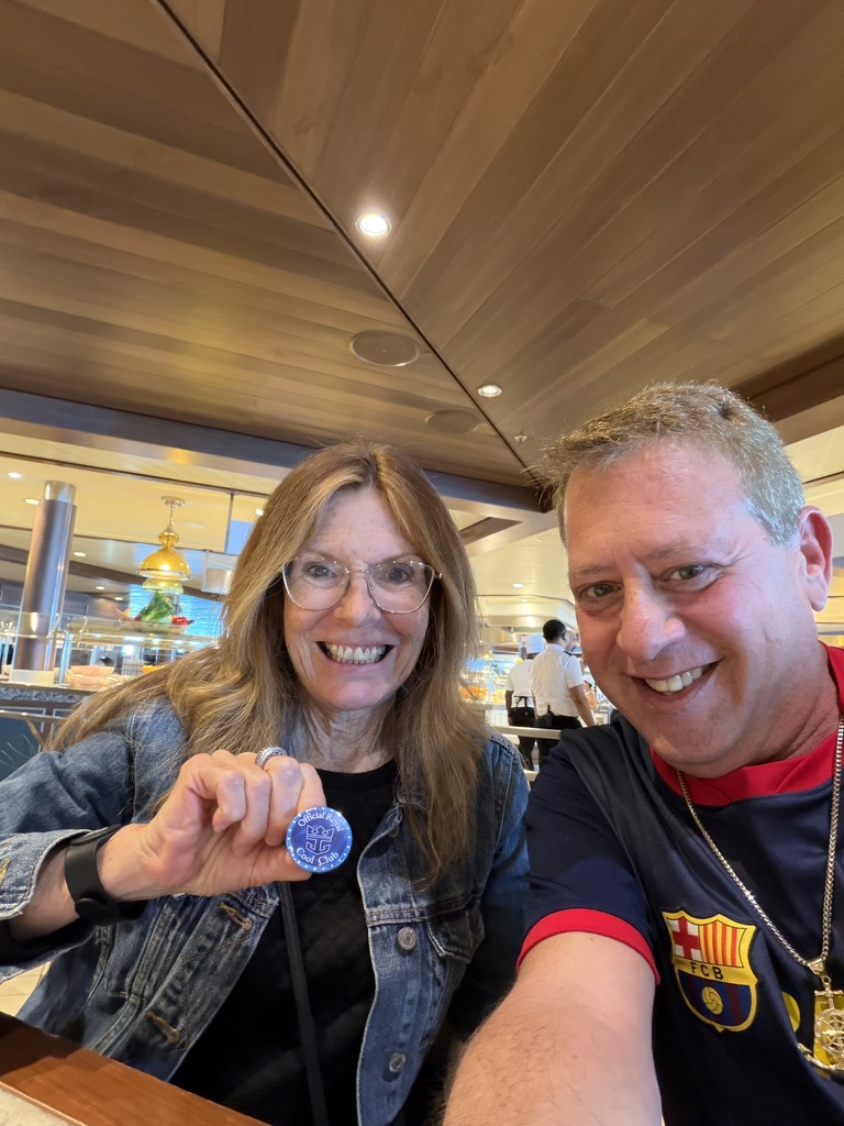 A keepsake passed across the table: Scott A. Astin seated beside a fellow traveler holding a blue keepsake pin