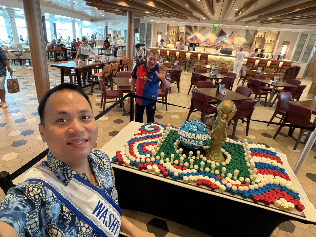 A celebration made by hand: A shipboard team member posing beside a football-themed cake display