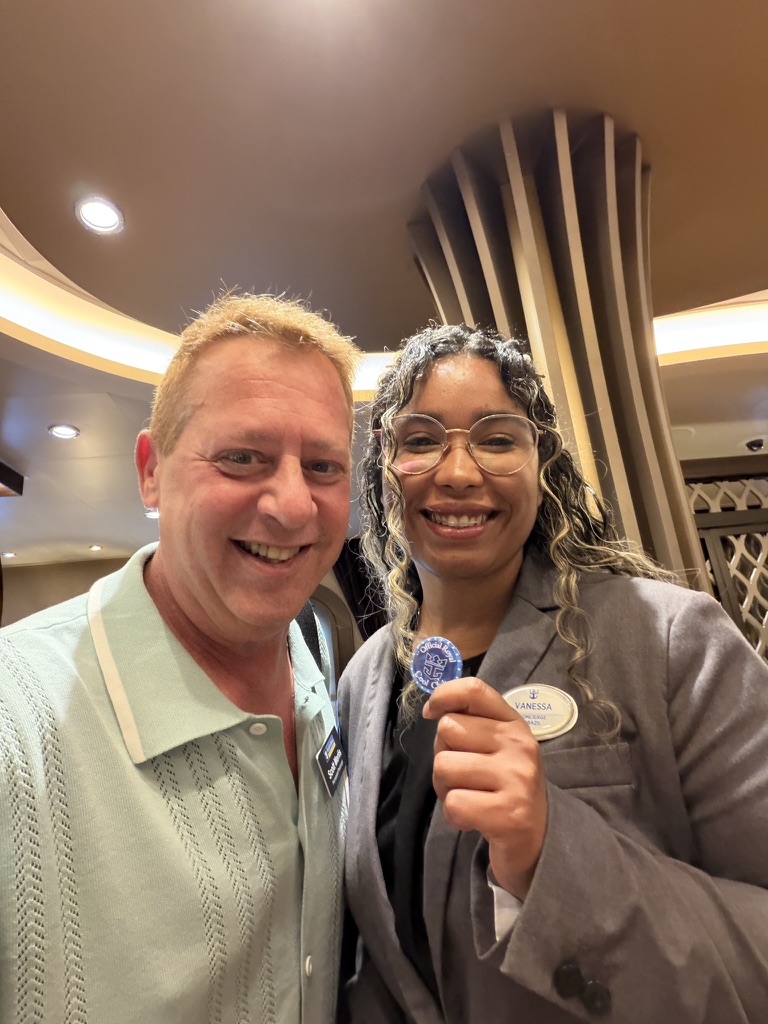 A moment of recognition: Scott A. Astin smiling beside a fellow traveler holding a blue keepsake pin