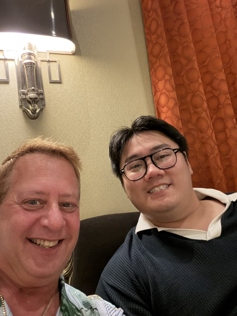 An evening conversation worth keeping: Scott A. Astin seated beside a fellow traveler wearing glasses