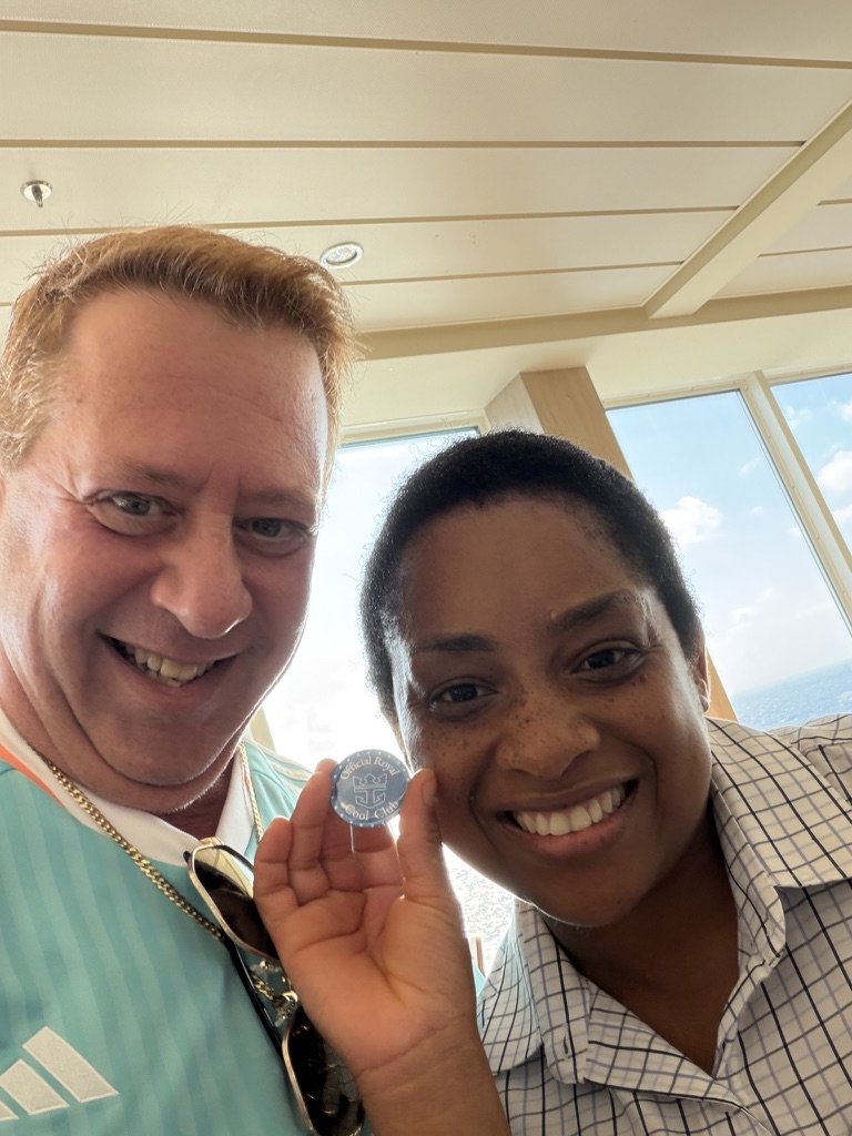 A hello that became a photograph: Scott A. Astin beside a smiling fellow traveler holding a blue keepsake pin near a window