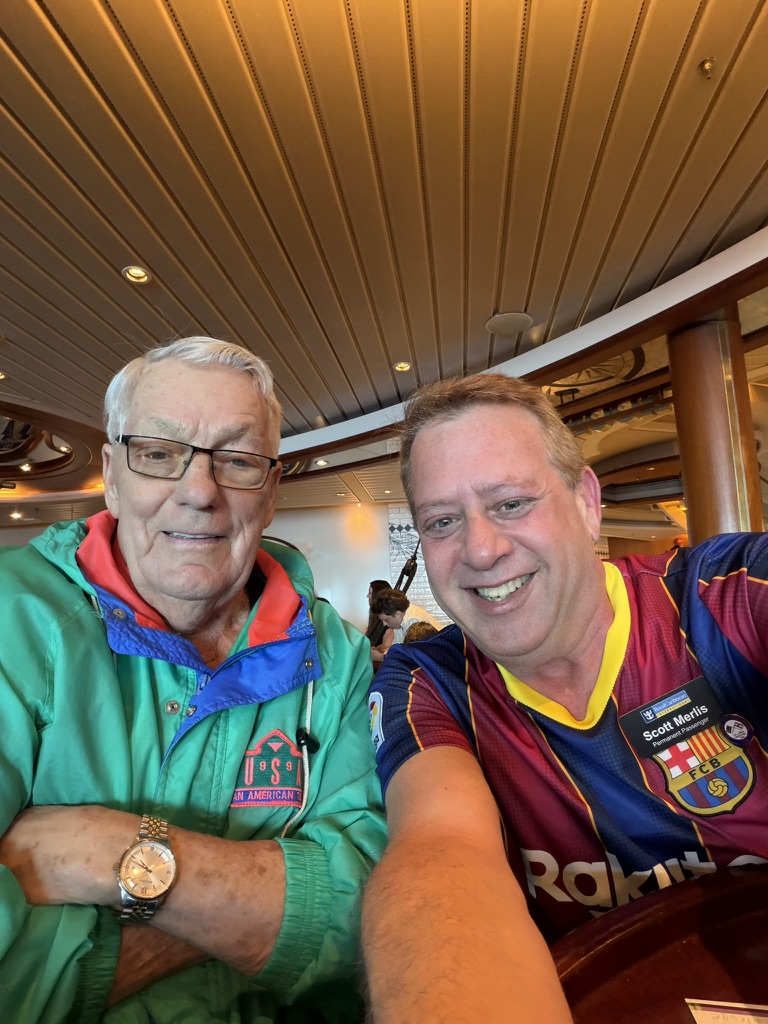 A familiar face returns: Scott A. Astin seated beside a fellow traveler in a green jacket