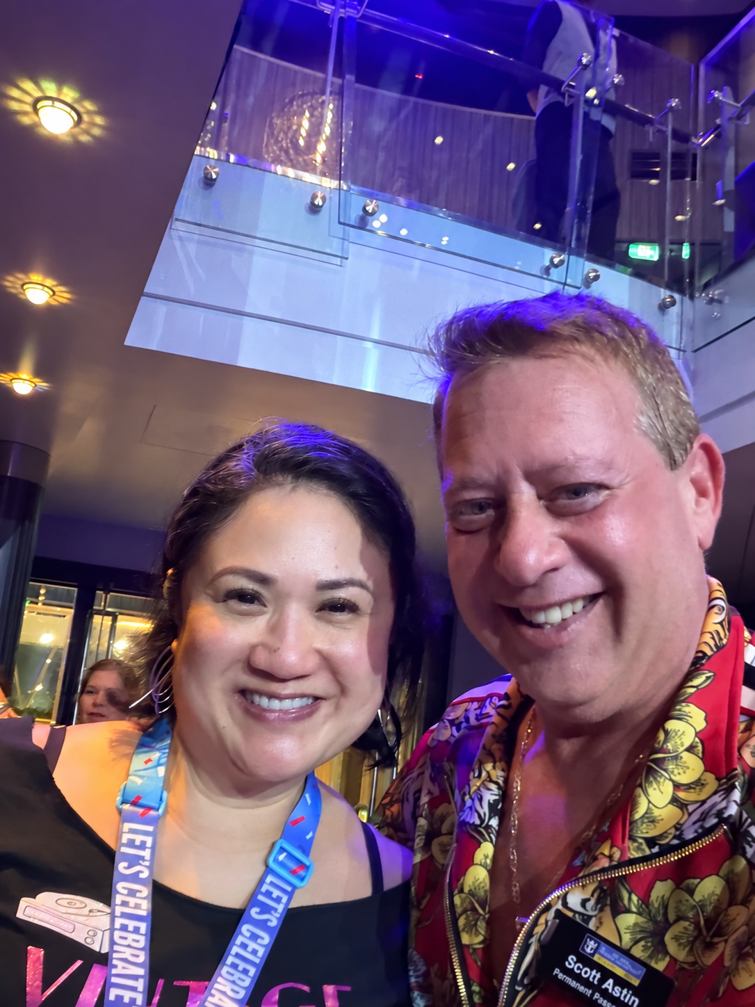 The night takes on a little color: Scott A. Astin smiling with a fellow traveler in a purple-lit ship atrium