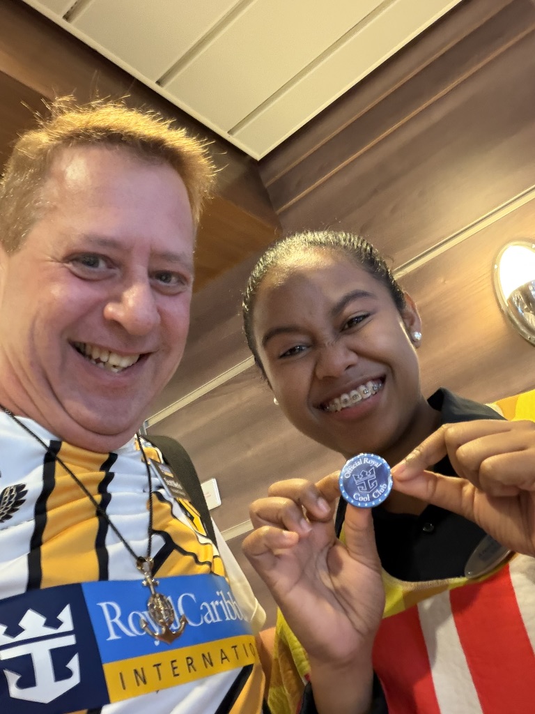 A shipboard moment with sparkle: Scott A. Astin smiling with a fellow traveler holding a blue keepsake pin