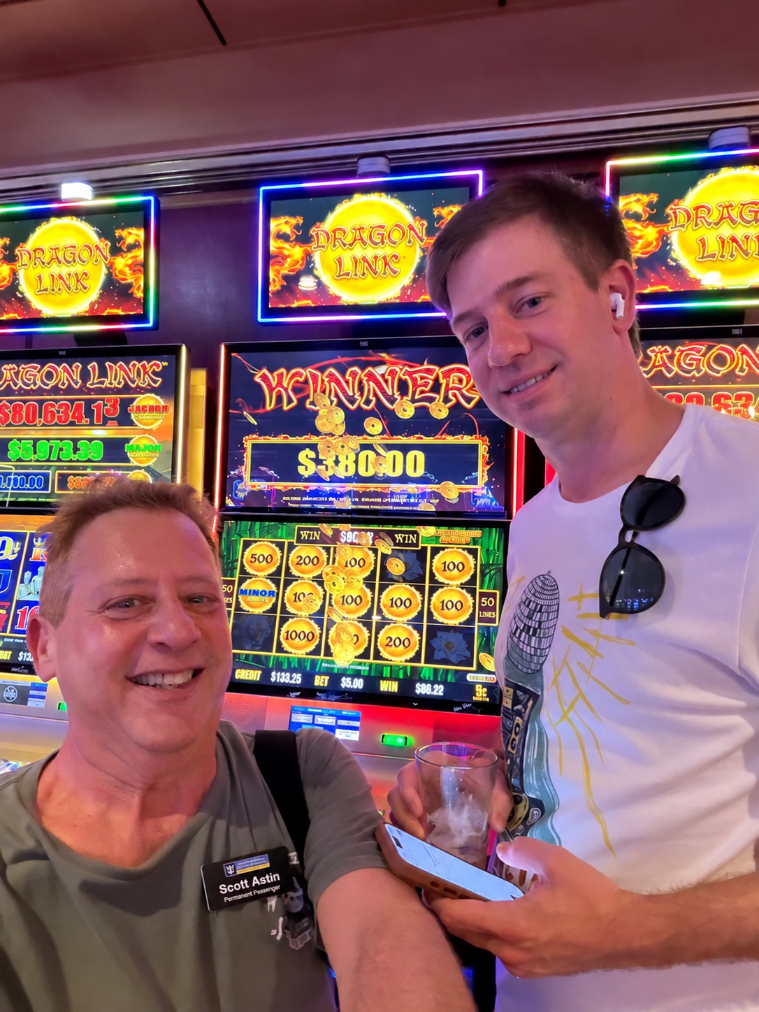 A jackpot moment shared with a friend: Scott A. Astin seated with a fellow traveler in front of a Dragon Link win screen
