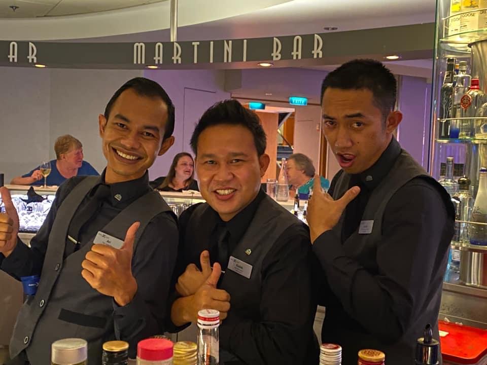 Three bartenders smiling behind the Martini Bar