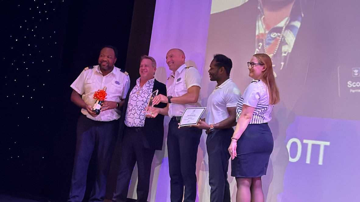 Scott Astin holding his Pinnacle recognition onstage with the Navigator of the Seas team
